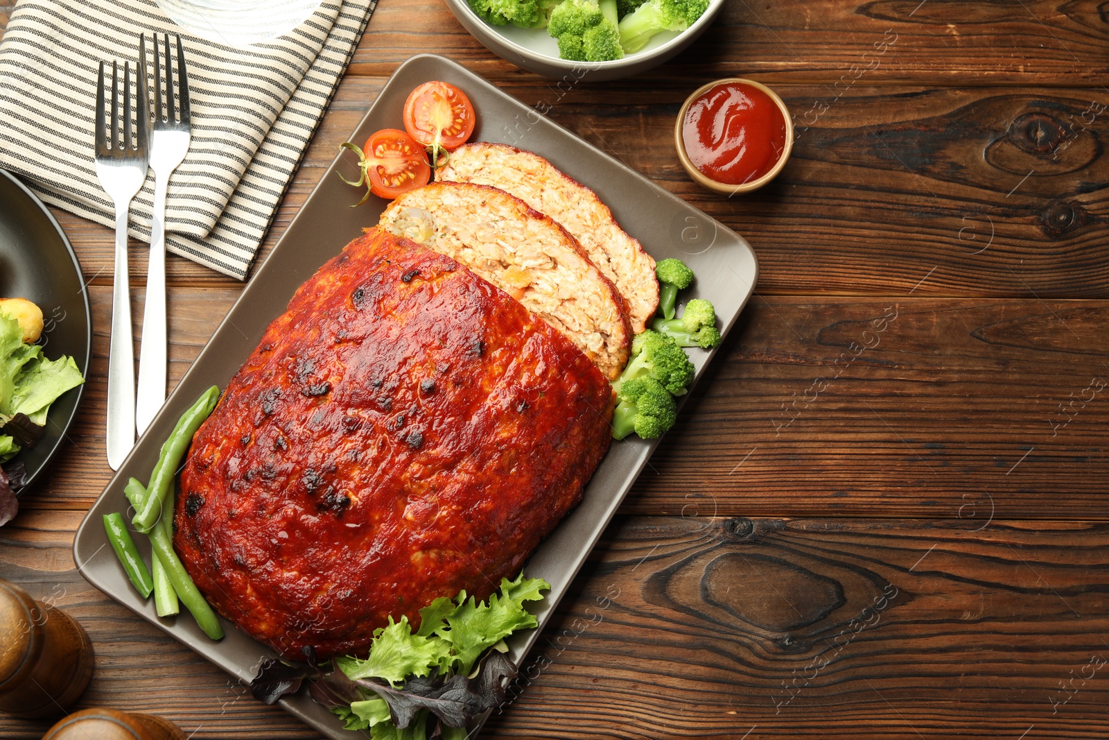 Photo of Delicious turkey meatloaf with vegetables served on wooden table, flat lay. Space for text