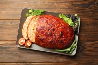 Photo of Delicious turkey meatloaf with vegetables on wooden table, top view