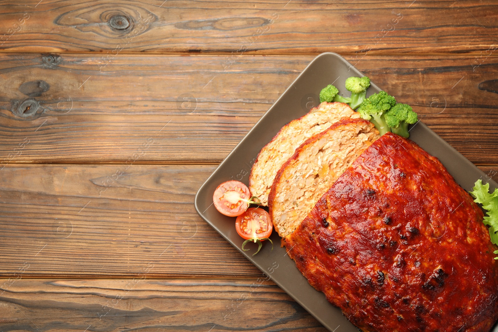 Photo of Delicious turkey meatloaf with vegetables on wooden table, top view. Space for text