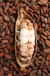 Cocoa pod on beans as background, top view