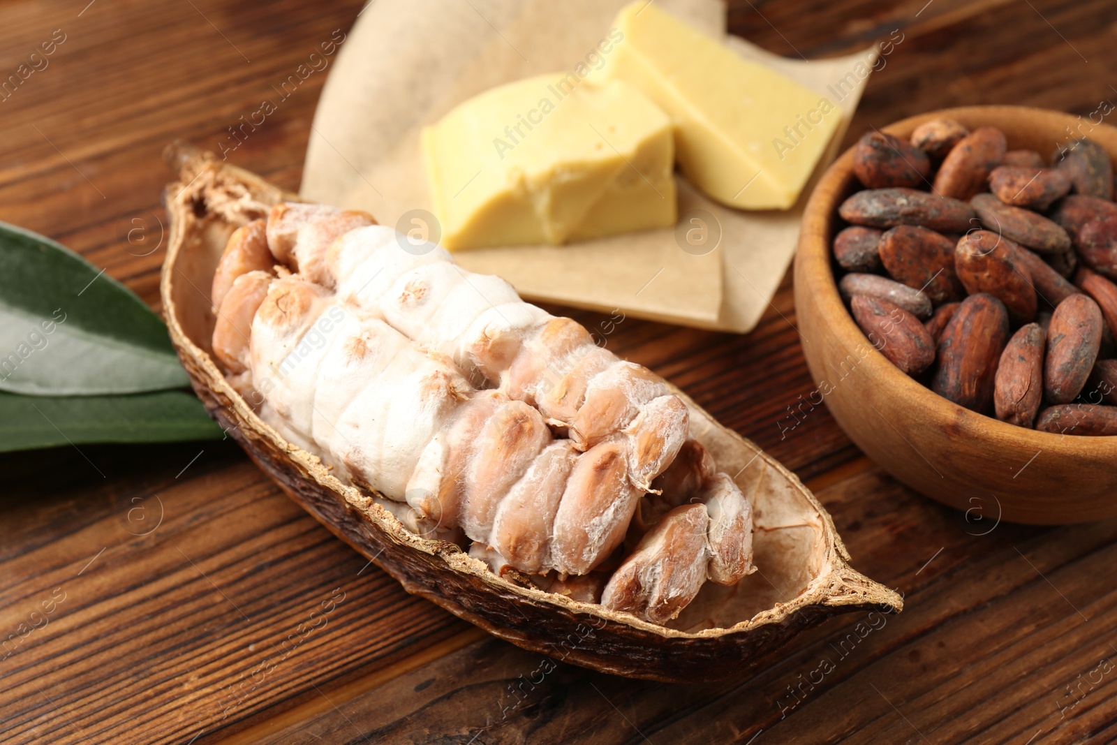 Photo of Cocoa pod with beans and butter on wooden table, closeup