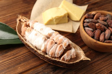 Photo of Cocoa pod with beans and butter on wooden table, closeup