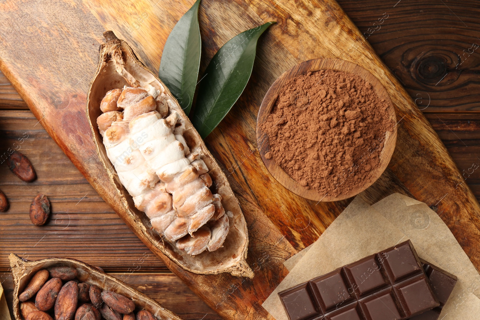 Photo of Cocoa pods with beans and chocolate on wooden table, flat lay