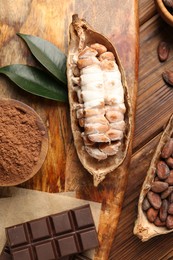 Photo of Cocoa pods with beans and chocolate on wooden table, flat lay