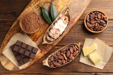 Cocoa pods with beans, chocolate and butter on wooden table, flat lay