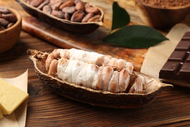 Photo of Cocoa pods with beans, chocolate and butter on wooden table, closeup