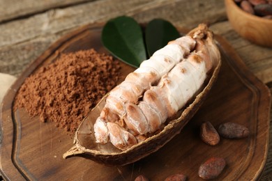 Photo of Cocoa pod with beans and powder on wooden table, closeup