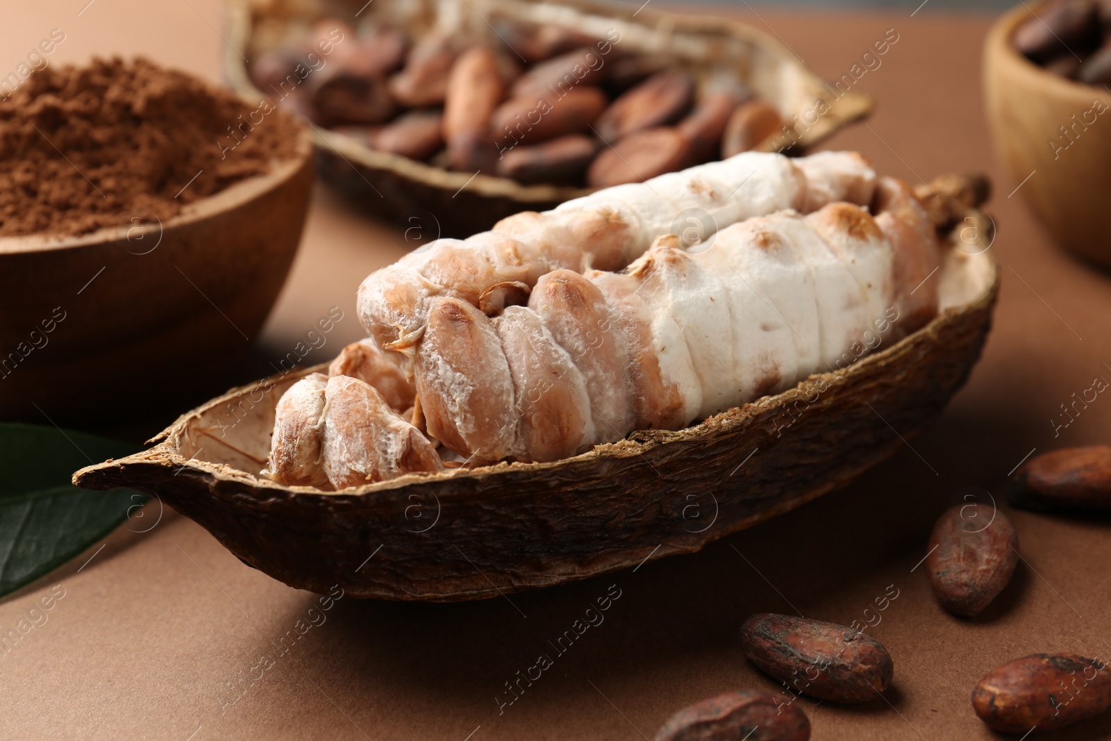 Photo of Cocoa pod with beans and powder on brown background, closeup