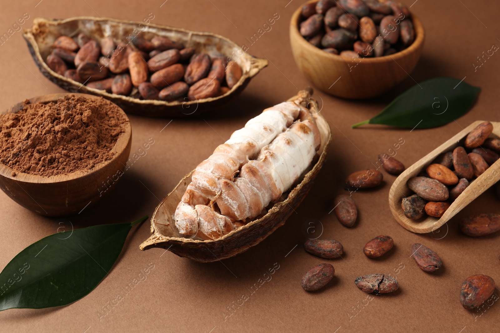 Photo of Cocoa pods with beans and powder on brown background, closeup