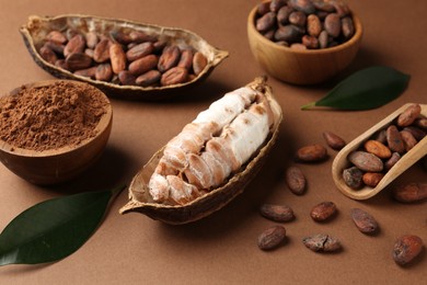 Photo of Cocoa pods with beans and powder on brown background, closeup