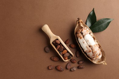 Cocoa pod with beans on brown background, flat lay. Space for text