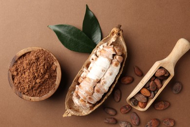 Photo of Cocoa pod with beans and powder on brown background, flat lay