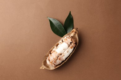 Cocoa pod with beans on brown background, top view