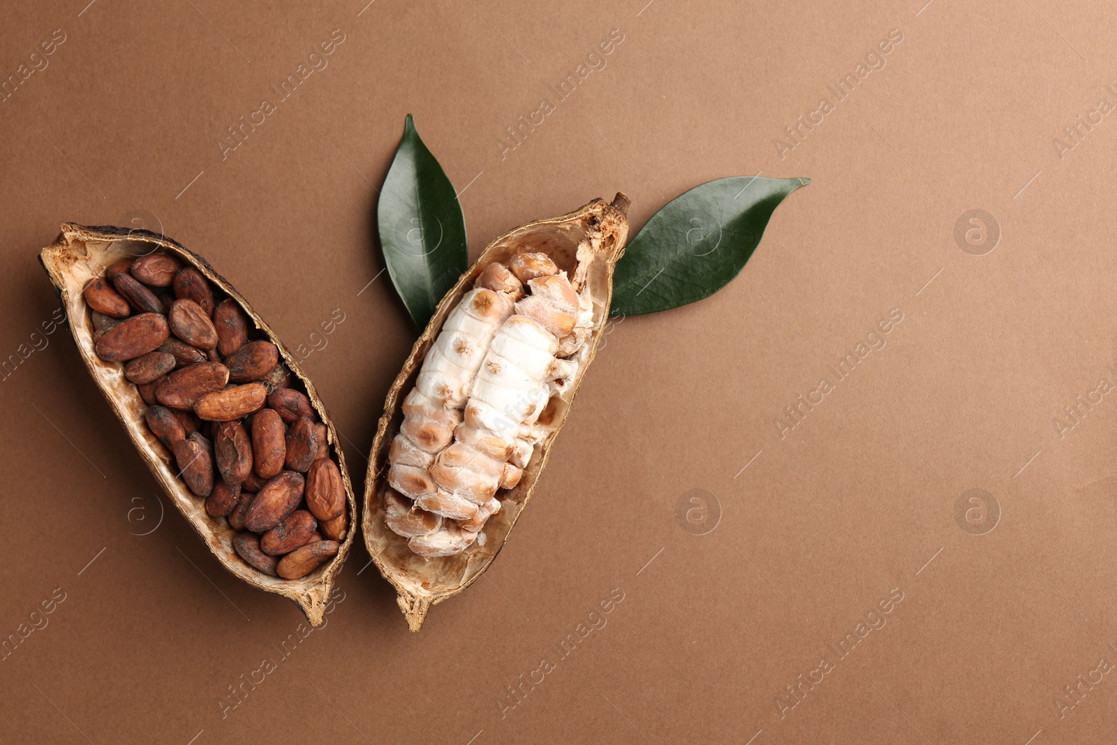 Photo of Cocoa pods with beans on brown background, top view. Space for text