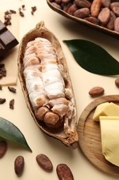 Photo of Cocoa pods with beans, butter and chocolate on beige background, closeup