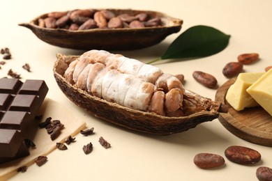 Cocoa pods with beans, butter and chocolate on beige background, closeup