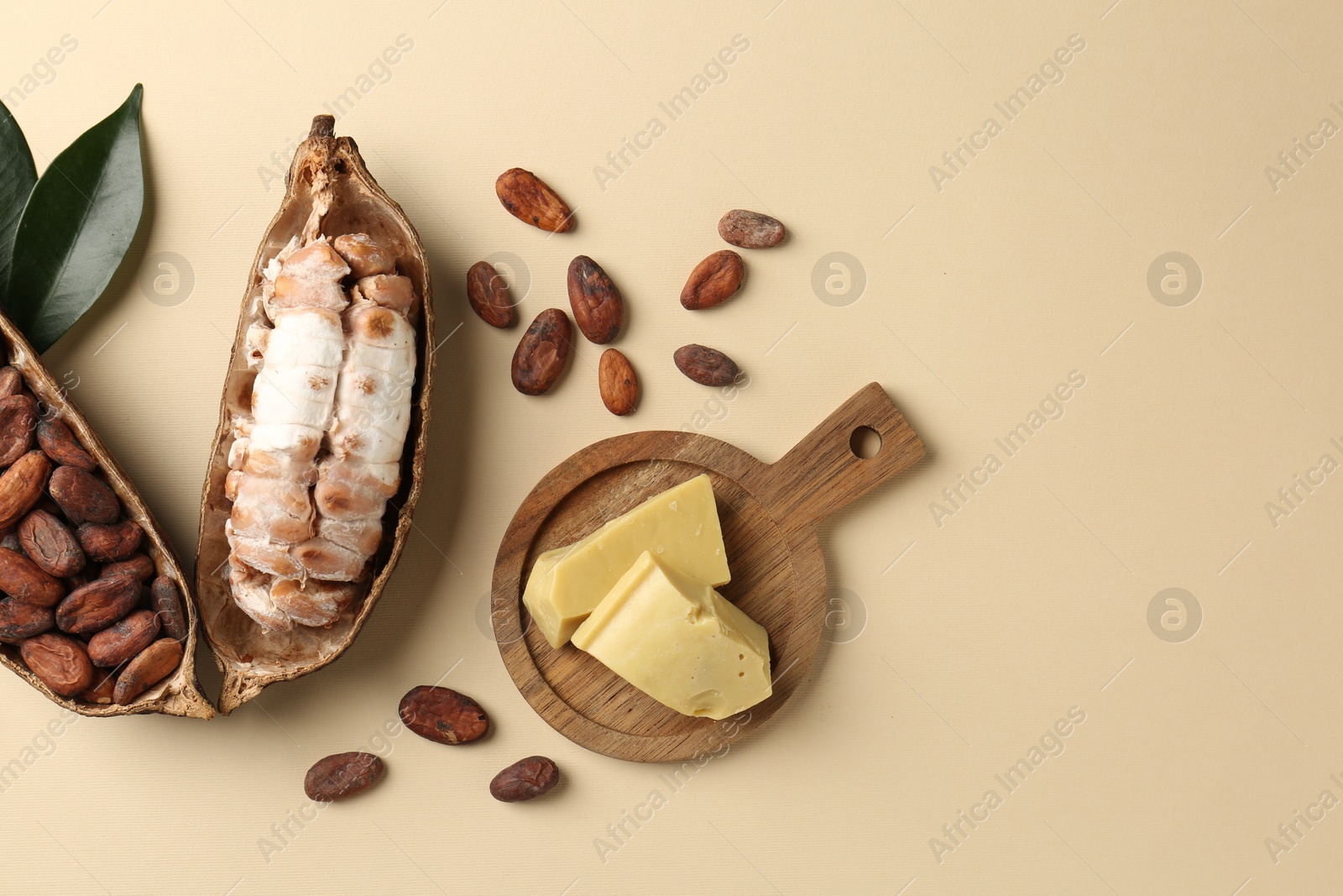 Photo of Cocoa pods with beans and butter on beige background, flat lay. Space for text