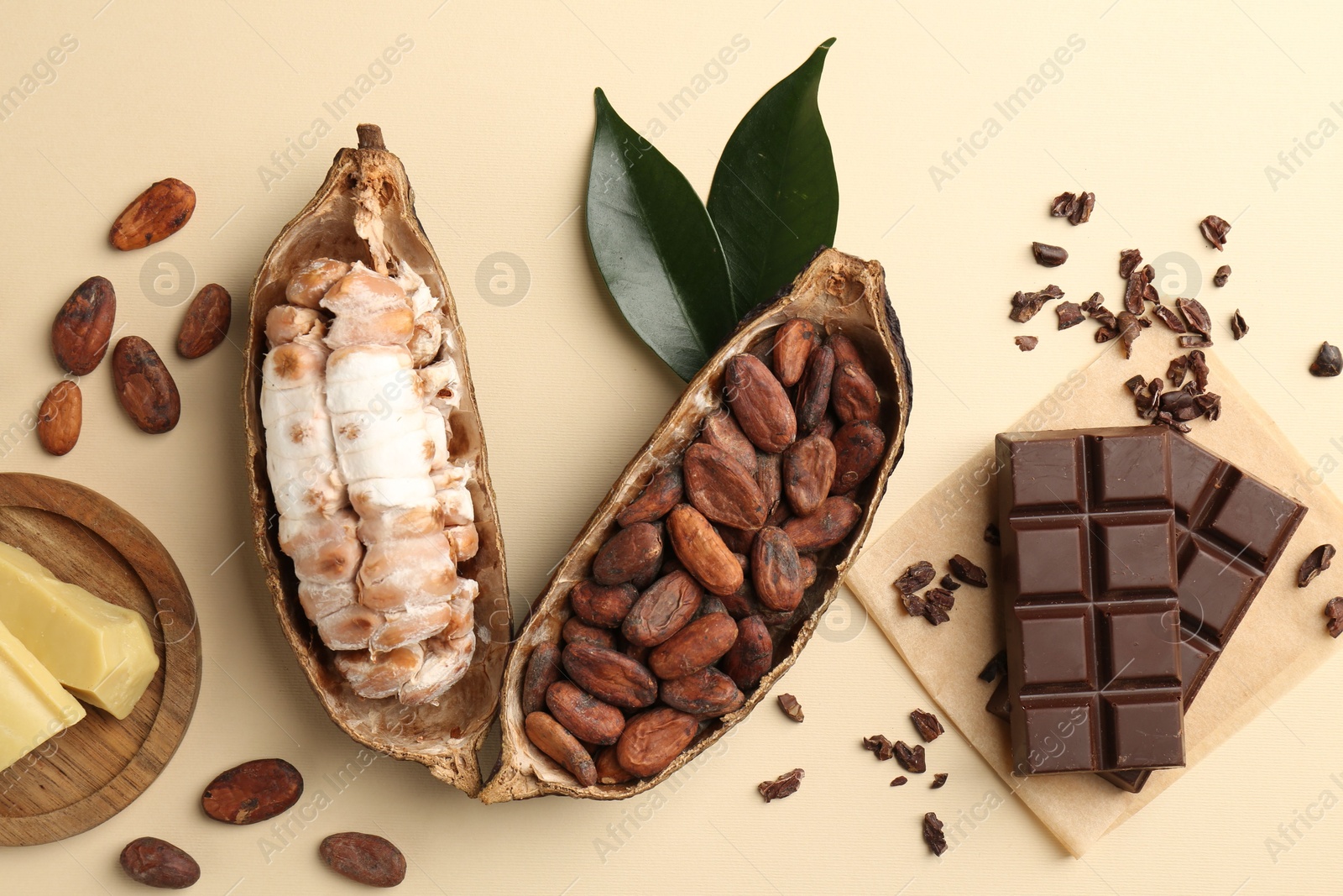 Photo of Cocoa pods with beans, butter and chocolate on beige background, flat lay