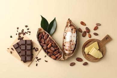 Cocoa pods with beans, butter and chocolate on beige background, flat lay