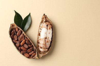 Cocoa pods with beans on beige background, top view. Space for text