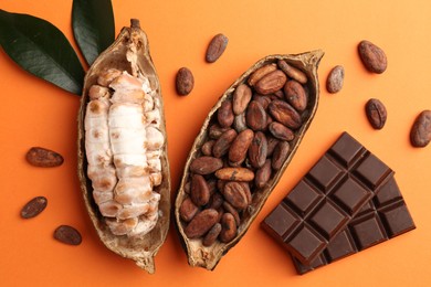 Cocoa pods with beans and chocolate on orange background, flat lay