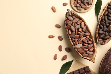 Photo of Cocoa pods with beans and chocolate on beige background, flat lay. Space for text