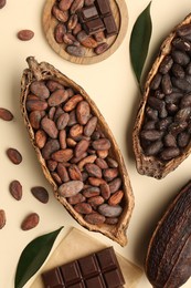 Cocoa pods with beans and chocolate on beige background, flat lay