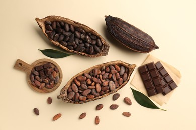 Photo of Cocoa pods with beans and chocolate on beige background, flat lay