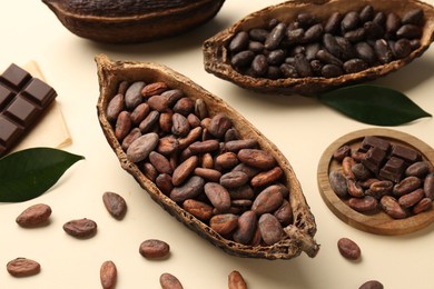 Cocoa pods with beans and chocolate on beige background