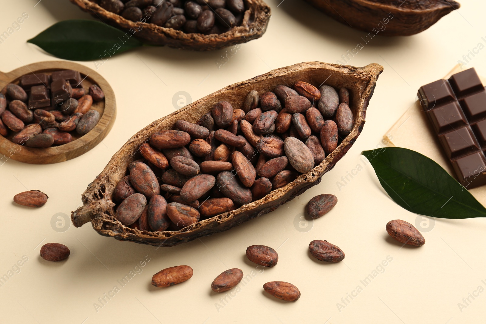 Photo of Cocoa pods with beans and chocolate on beige background