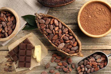 Cocoa pod with beans, powder, butter and chocolate on wooden table, flat lay