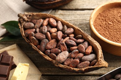 Photo of Cocoa pod with beans, powder, butter and chocolate on wooden table