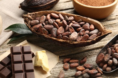 Photo of Cocoa pods with beans, powder, butter and chocolate on wooden table