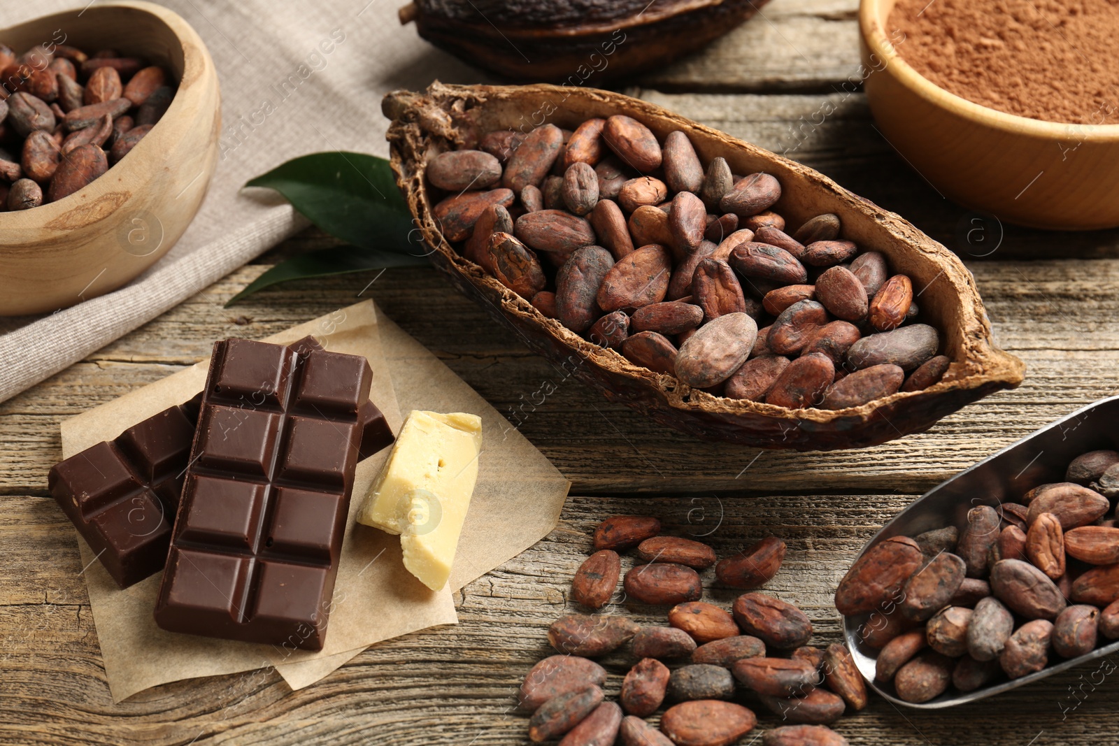 Photo of Cocoa pod with beans, powder, butter and chocolate on wooden table