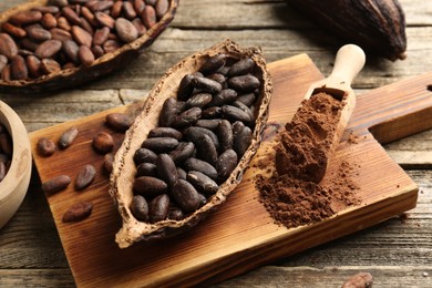 Photo of Cocoa pods with beans and powder on wooden table