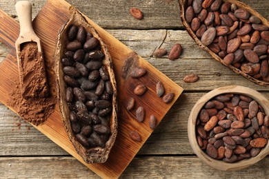 Cocoa pods with beans and powder on wooden table, flat lay