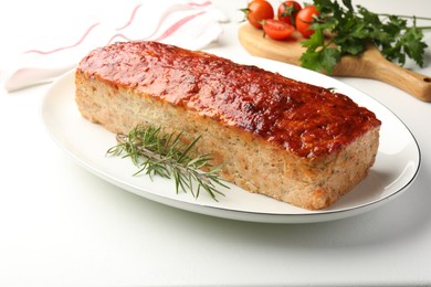 Photo of Delicious baked turkey meatloaf, rosemary, cherry tomatoes and parsley on white table, closeup