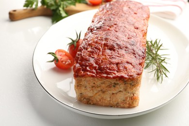 Photo of Delicious baked turkey meatloaf, rosemary and cherry tomatoes on white table, closeup