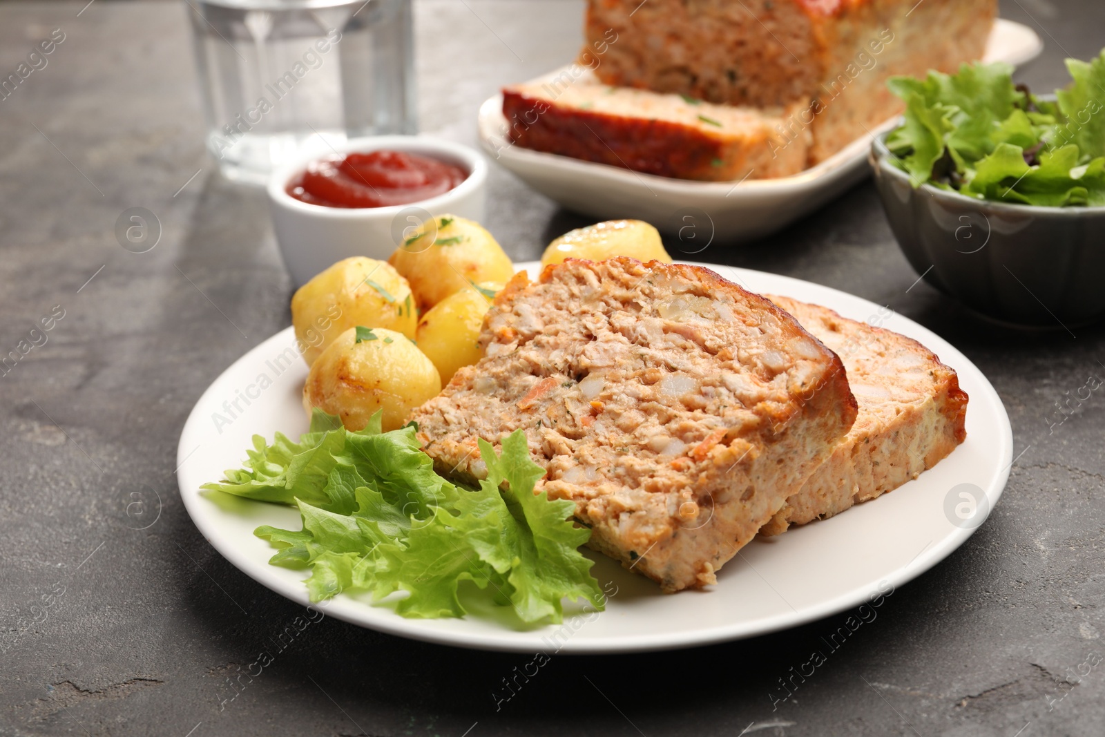 Photo of Delicious baked turkey meatloaf with potatoes served on grey table, closeup