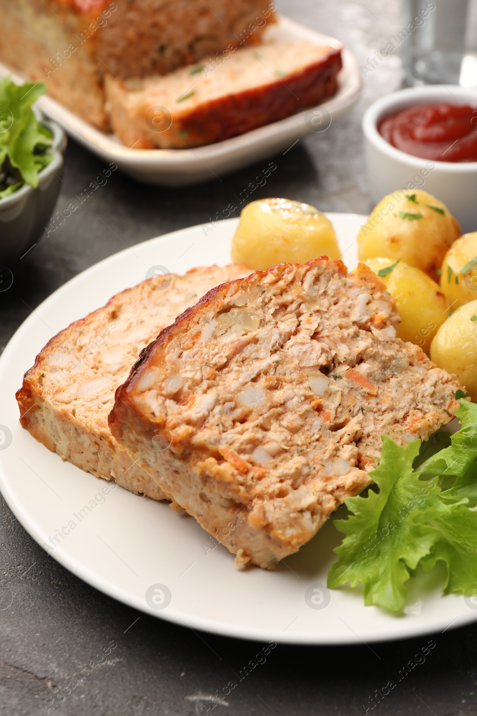 Photo of Delicious baked turkey meatloaf with potatoes served on grey table, closeup