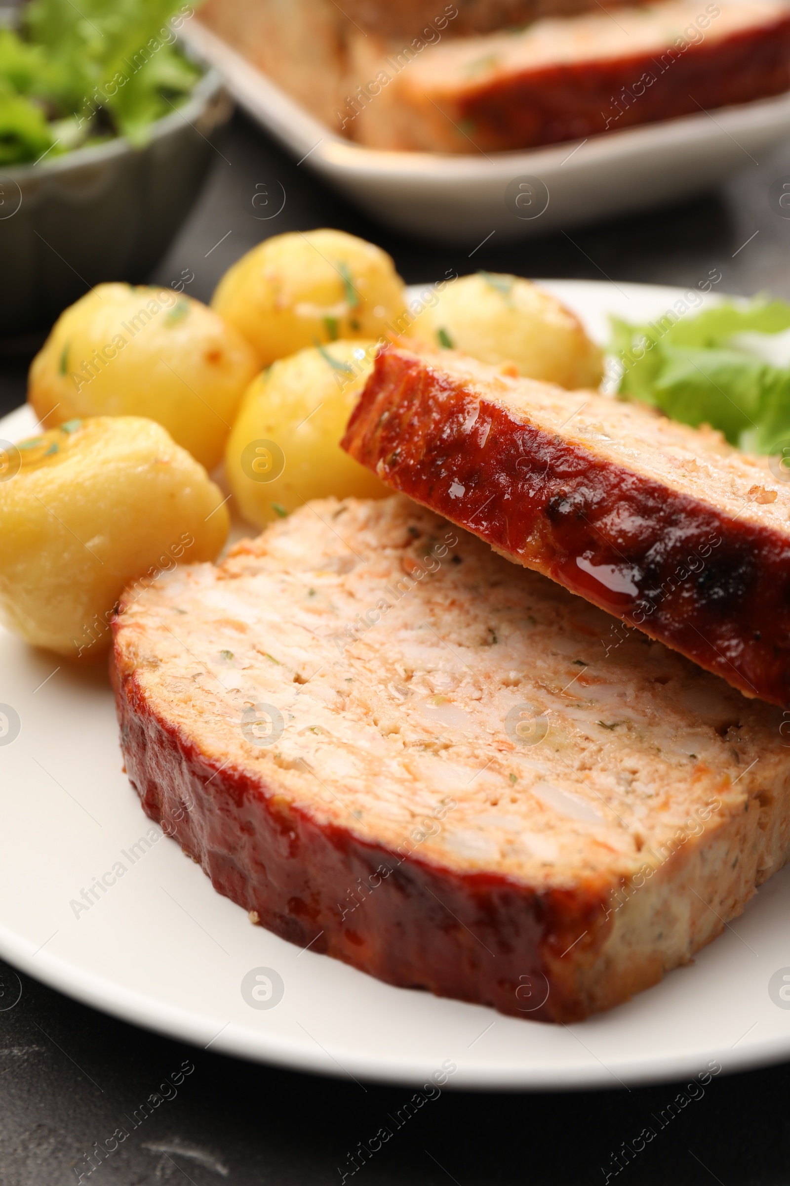 Photo of Delicious baked turkey meatloaf and potatoes on table, closeup