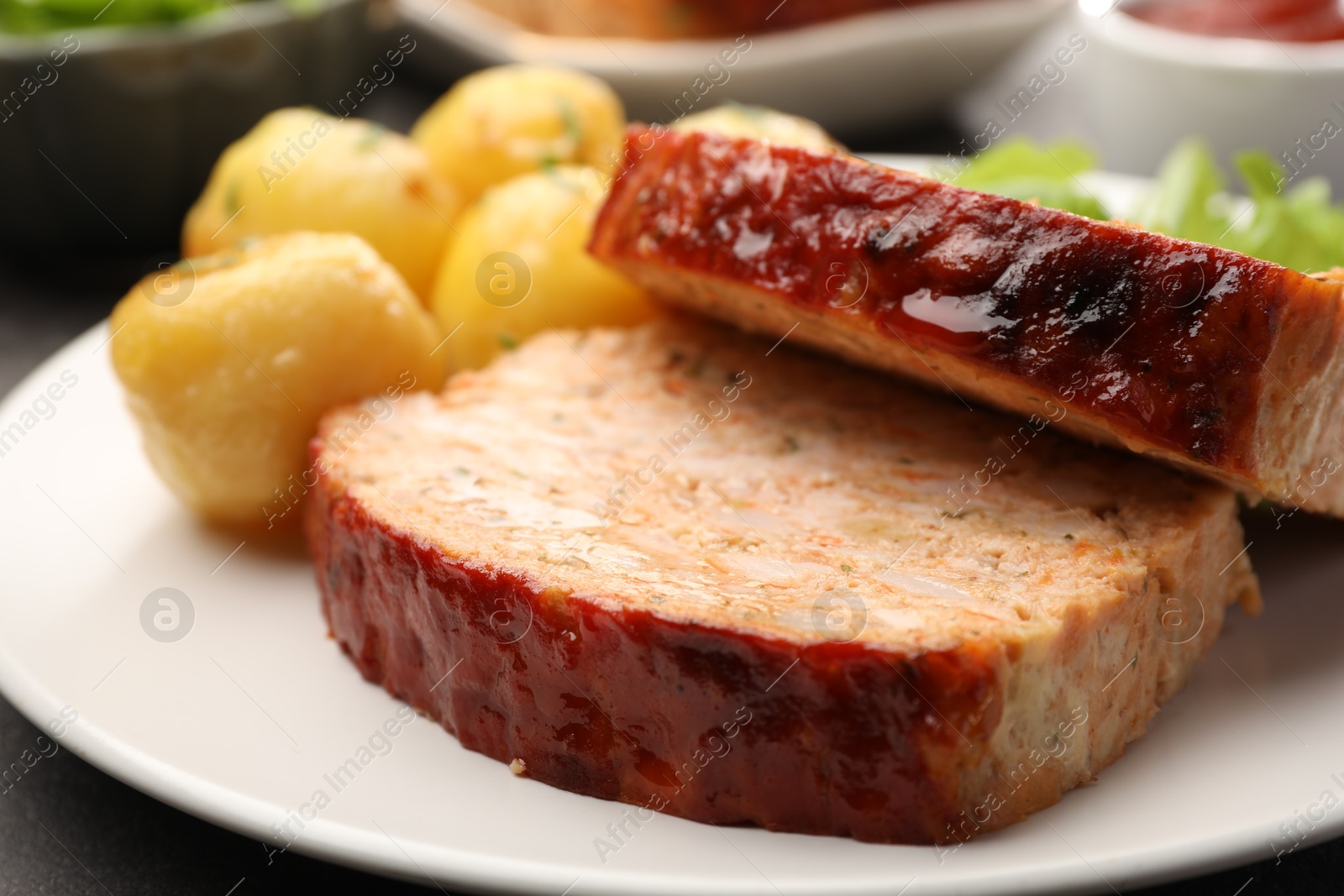 Photo of Delicious baked turkey meatloaf and potatoes on table, closeup