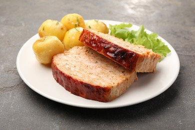 Photo of Delicious baked turkey meatloaf, potatoes and lettuce on grey table, closeup