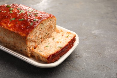 Photo of Delicious baked turkey meatloaf on grey table, closeup. Space for text