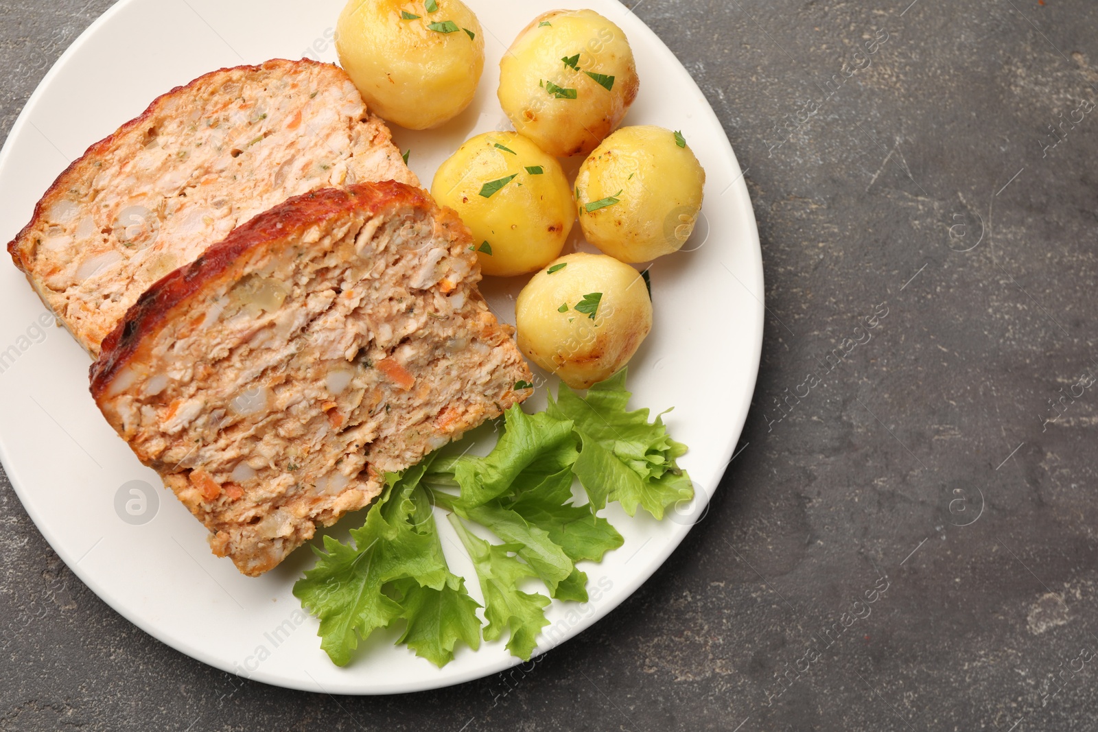 Photo of Delicious baked turkey meatloaf, potatoes and lettuce on grey table, top view. Space for text