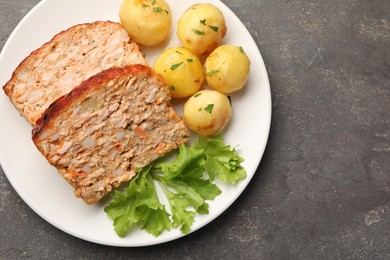 Photo of Delicious baked turkey meatloaf, potatoes and lettuce on grey table, top view. Space for text