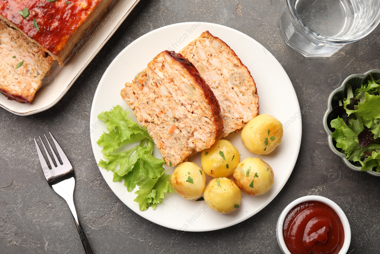 Photo of Delicious baked turkey meatloaf with vegetables served on grey table, flat lay