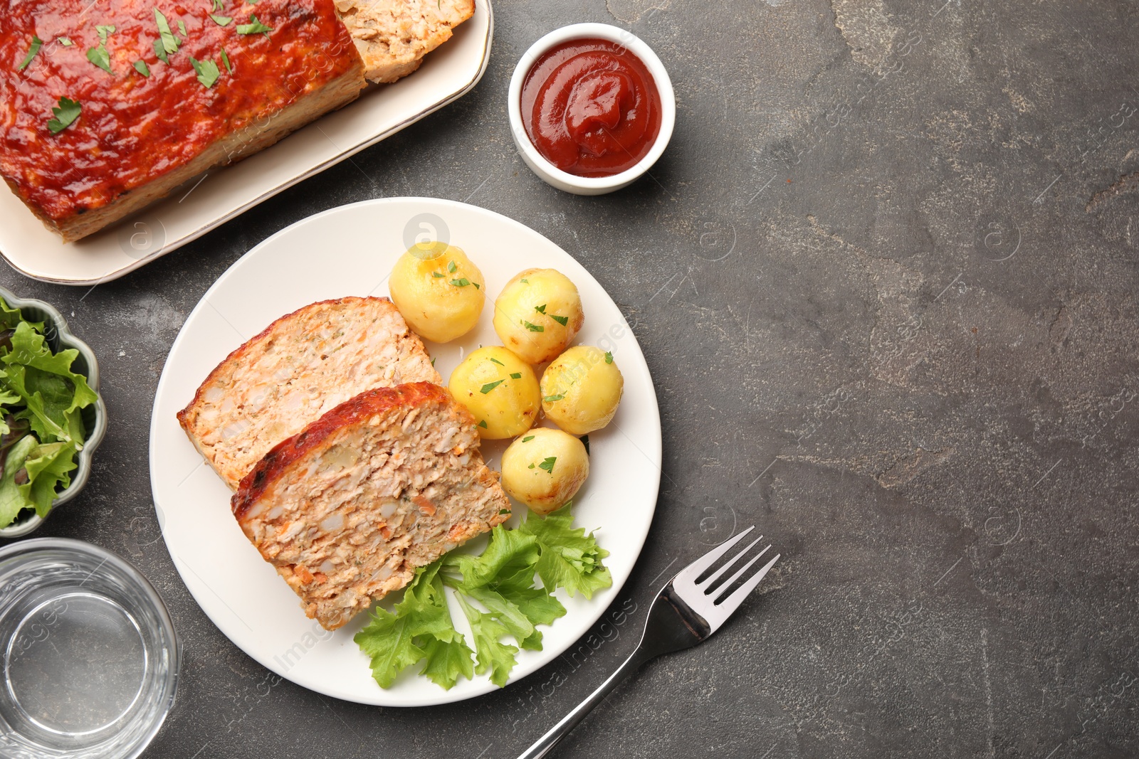 Photo of Delicious baked turkey meatloaf with vegetables served on grey table, flat lay. Space for text