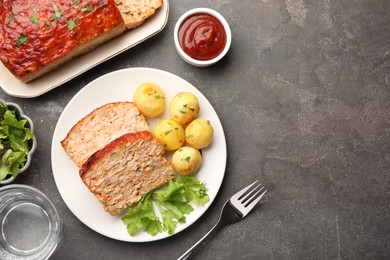 Photo of Delicious baked turkey meatloaf with vegetables served on grey table, flat lay. Space for text