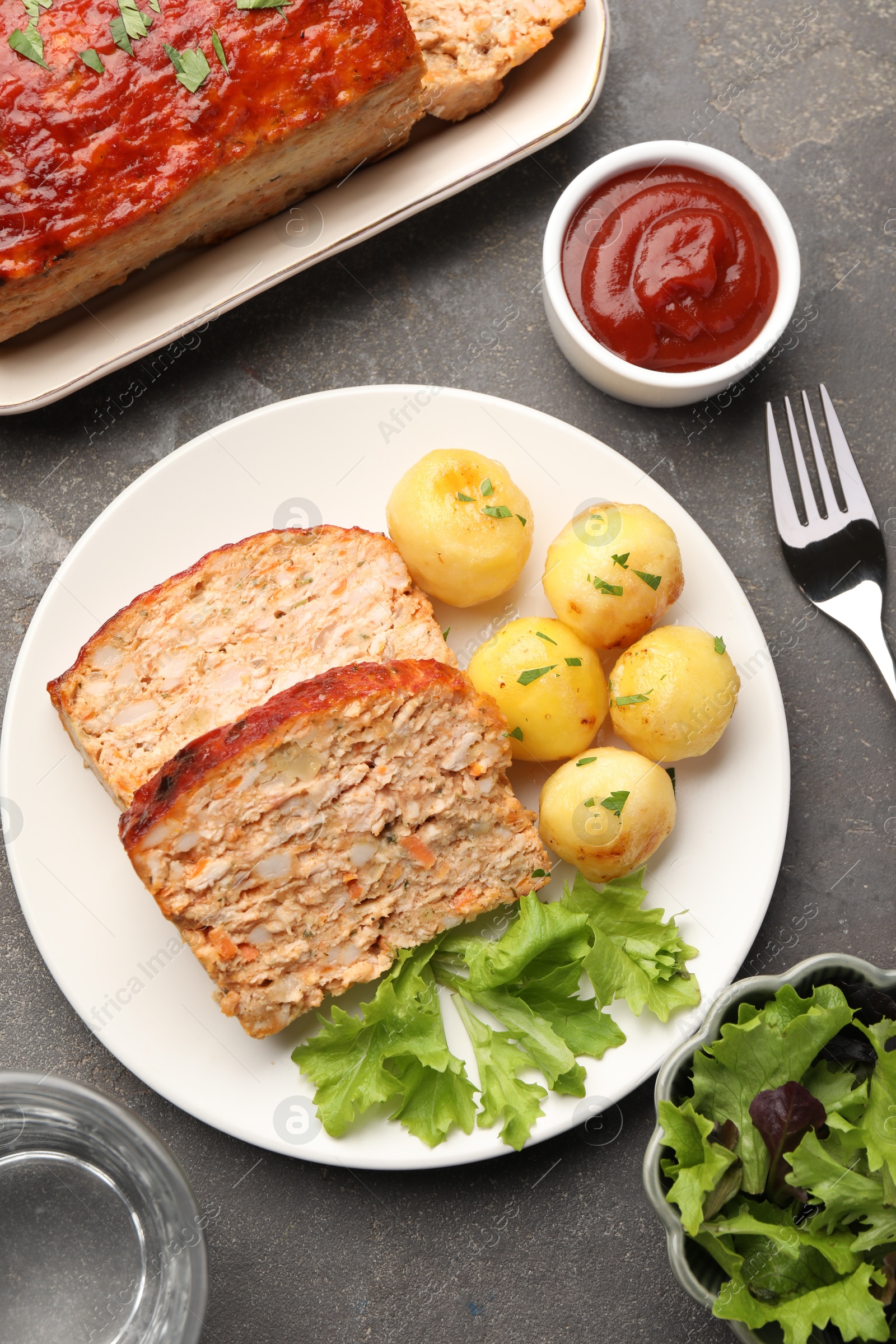 Photo of Delicious baked turkey meatloaf with vegetables served on grey table, flat lay